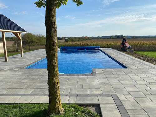 Landscaped Ontario backyard at golden hour with stone patio, lawn and cedars